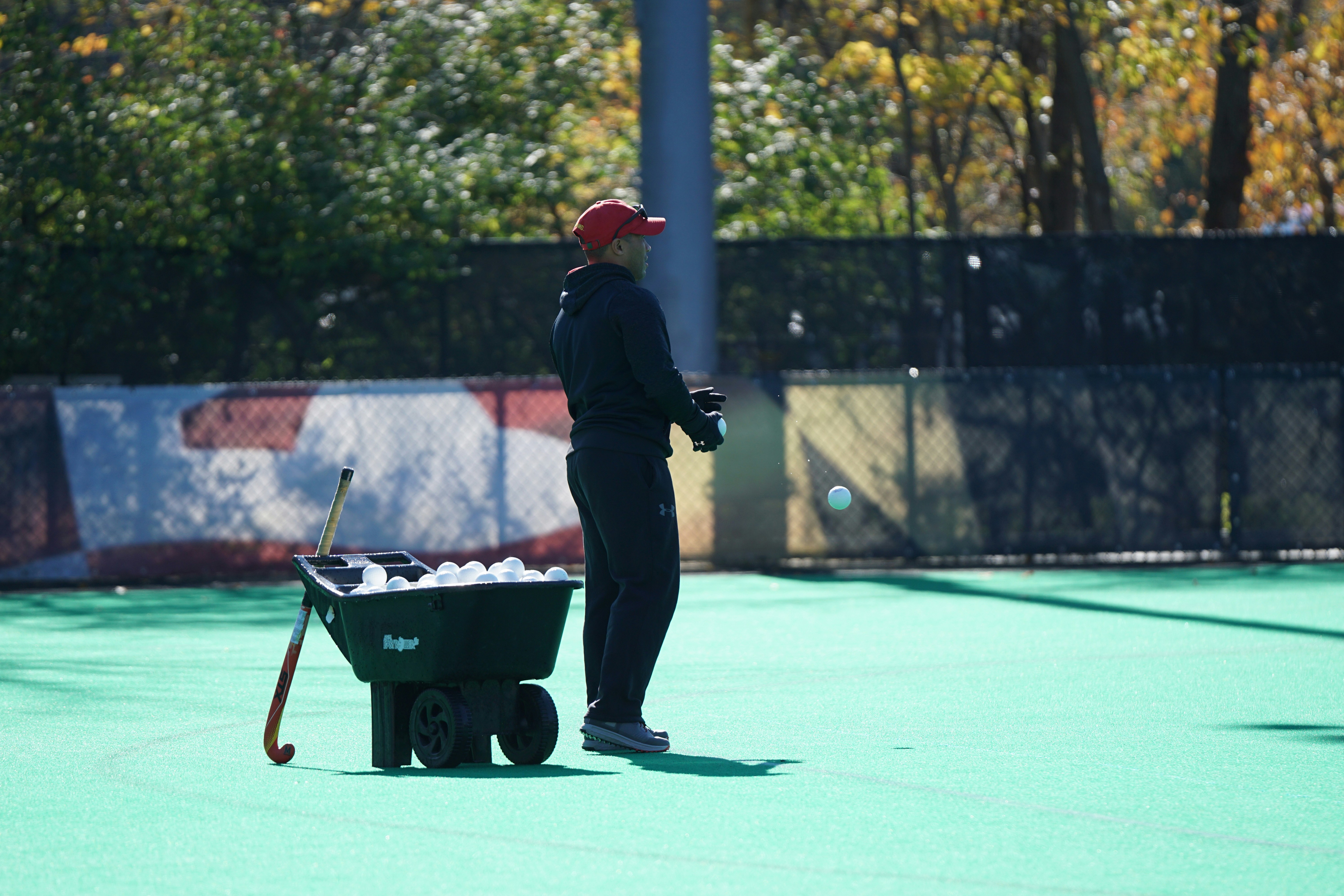 man standing beside wheelbarrow field hockey teams background