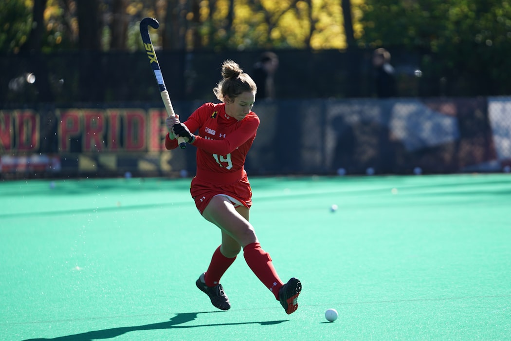 woman in red playing field hockey