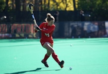 woman playing hockey on fields during daytime