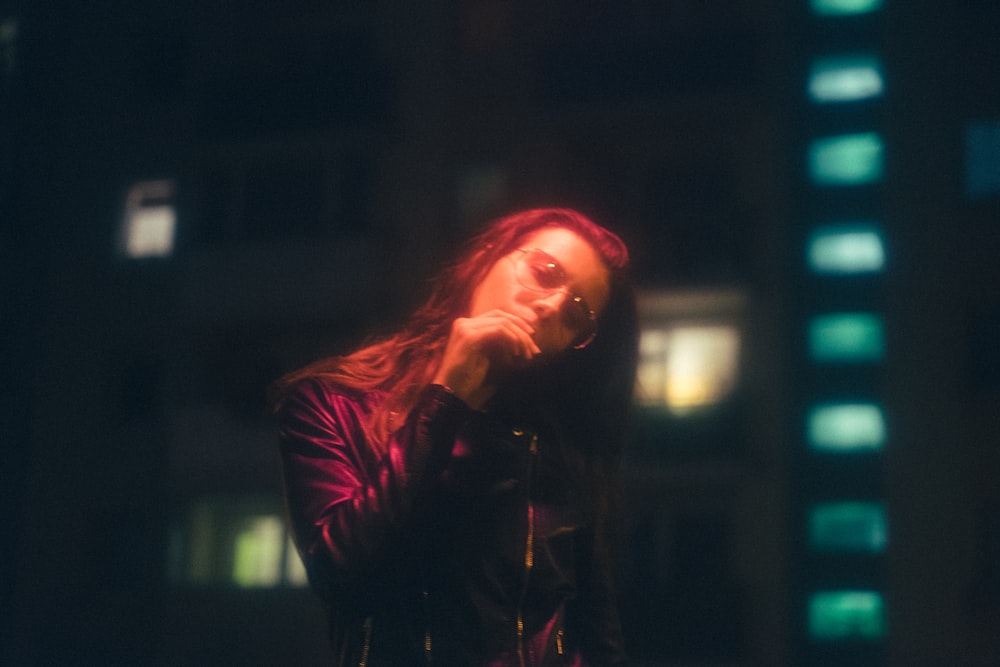 woman smoking cigarette while wearing black leather zip-up jacket