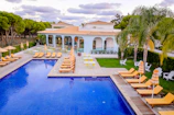 Inviting pool area framed by lush greenery and soft beige loungers.