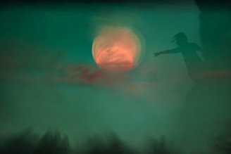 a blurry image of a person standing in front of a full moon
