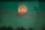 a blurry image of a person standing in front of a full moon