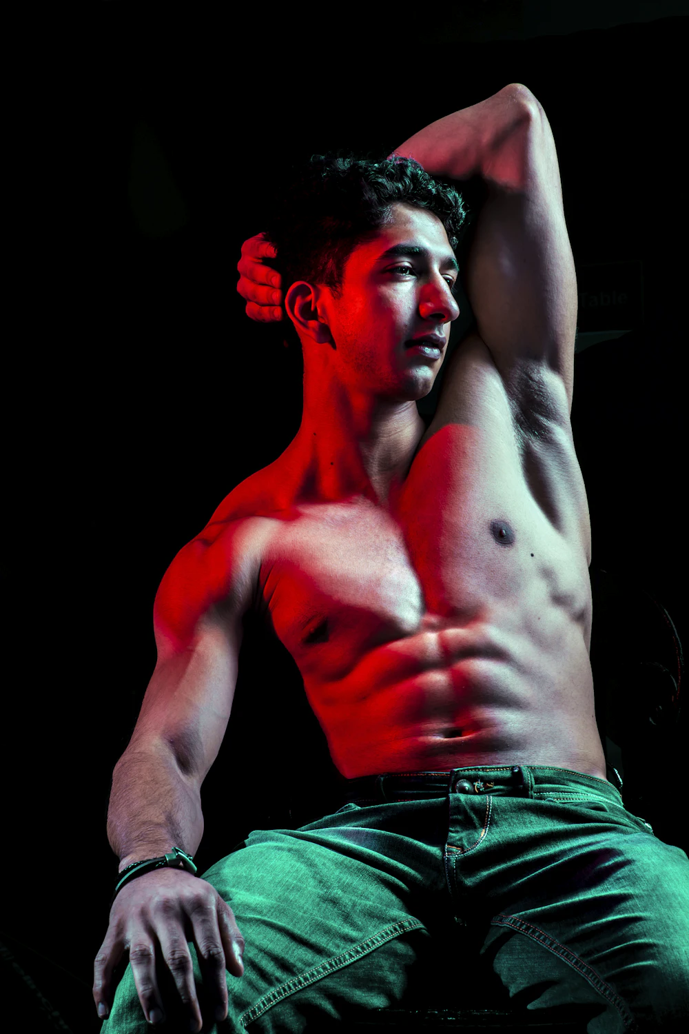 Man raising his arm, torso lit from the side