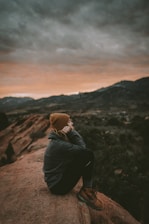 woman in green jacket sitting alone amongst calmness and serenity of nature.