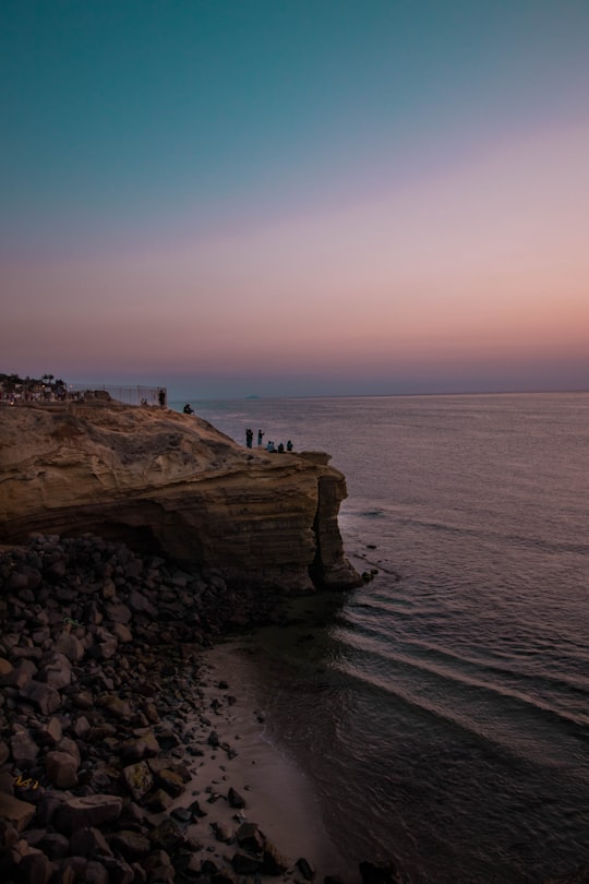 people standing on rockformation near ocean in Sunset Cliffs United States