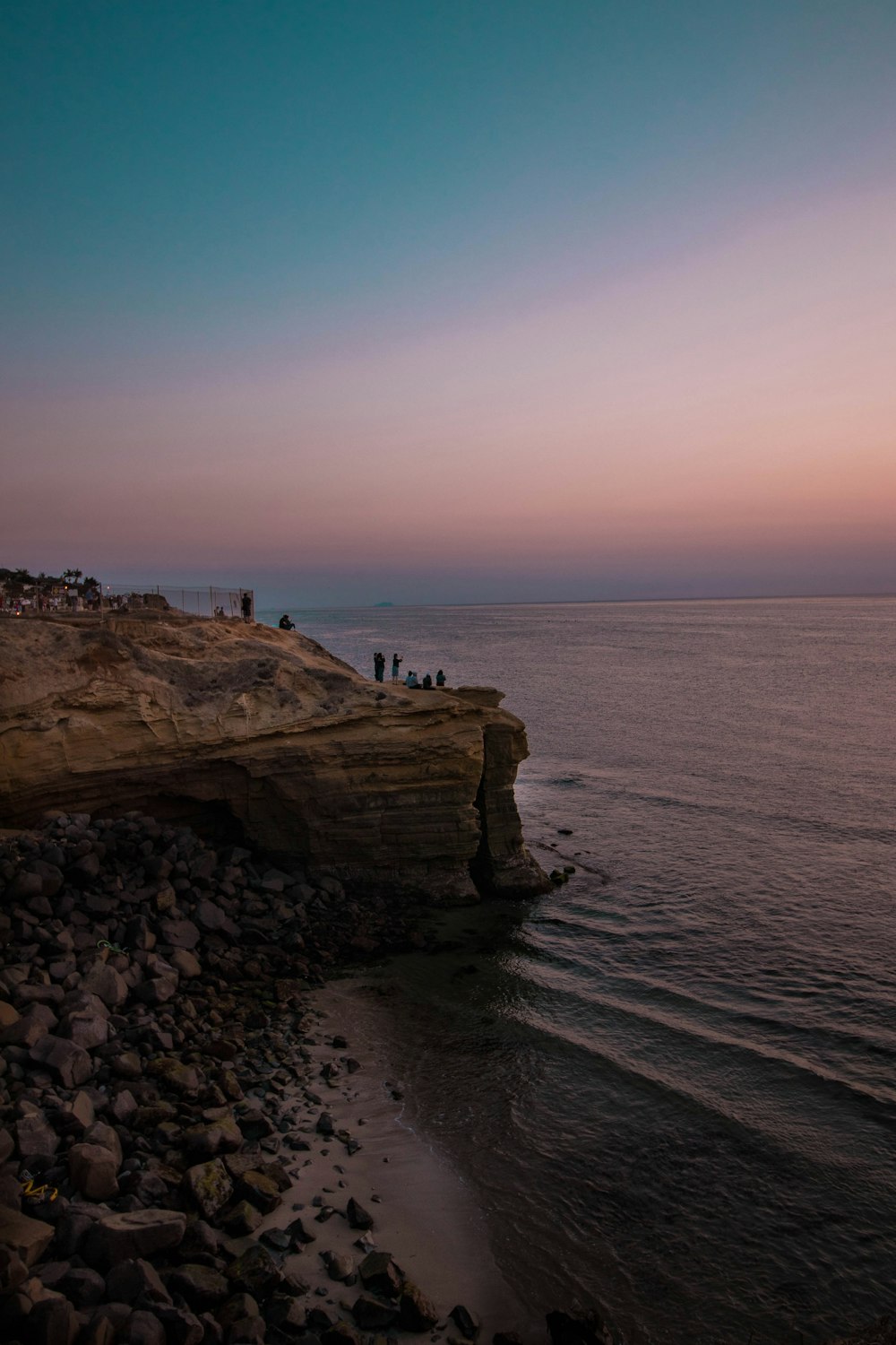 Pessoas em pé na formação rochosa perto do oceano