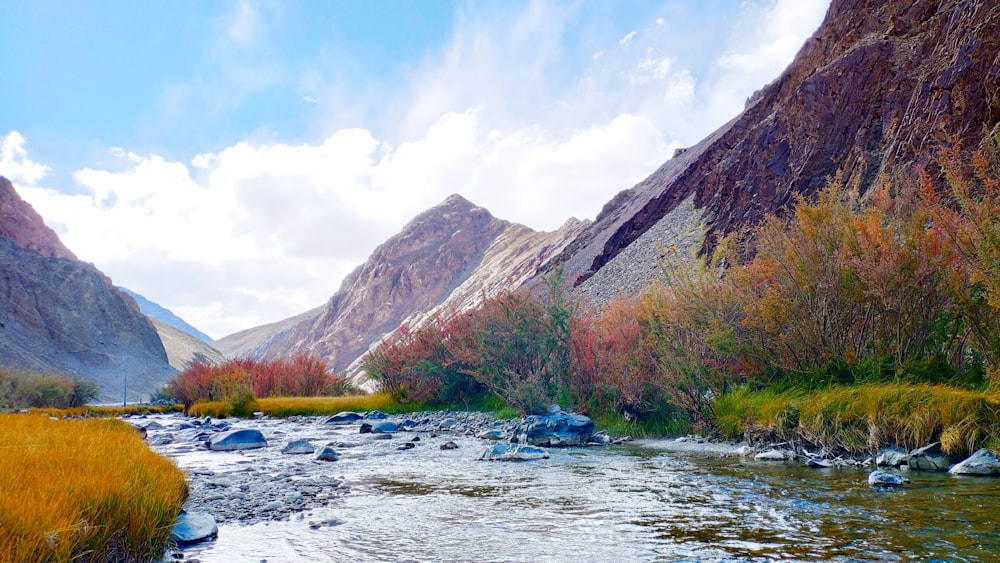 body of water between high mountains under blue and white sky during daytime