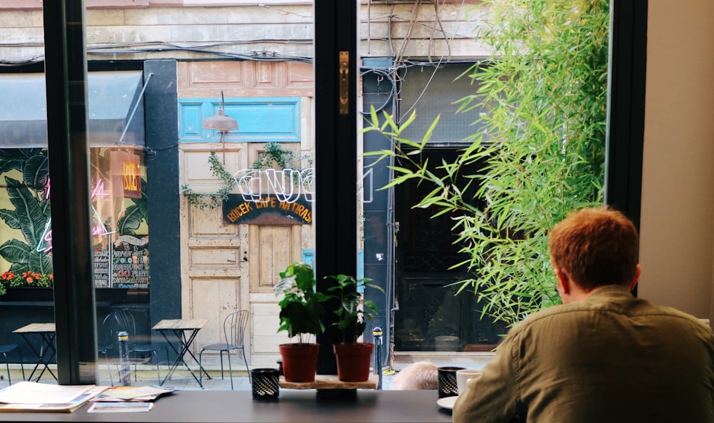 hombre sentado frente a una ventana de vidrio transparente