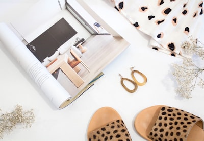 sandals and earrings placed next to opened catalog neutral google meet background