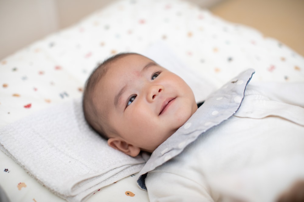 baby wearing white shirt lying on bed