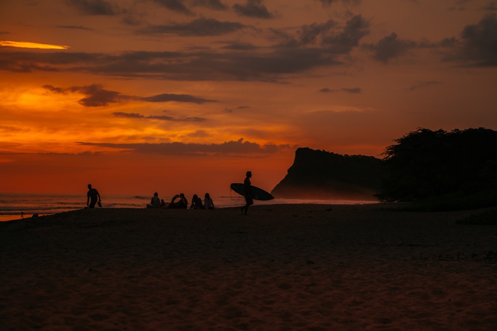 silhouette of man holding surfboard by the beach