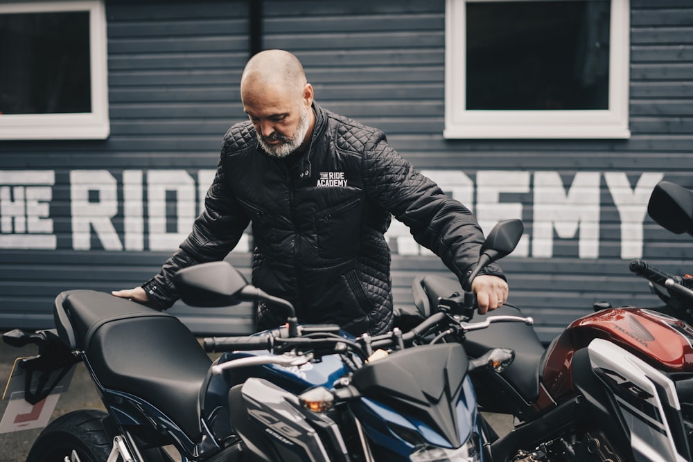 man holding black Honda CB motorcycle