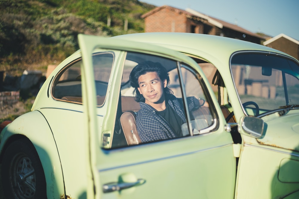 man in black crew-neck shirt in green Volkswagen Beetle