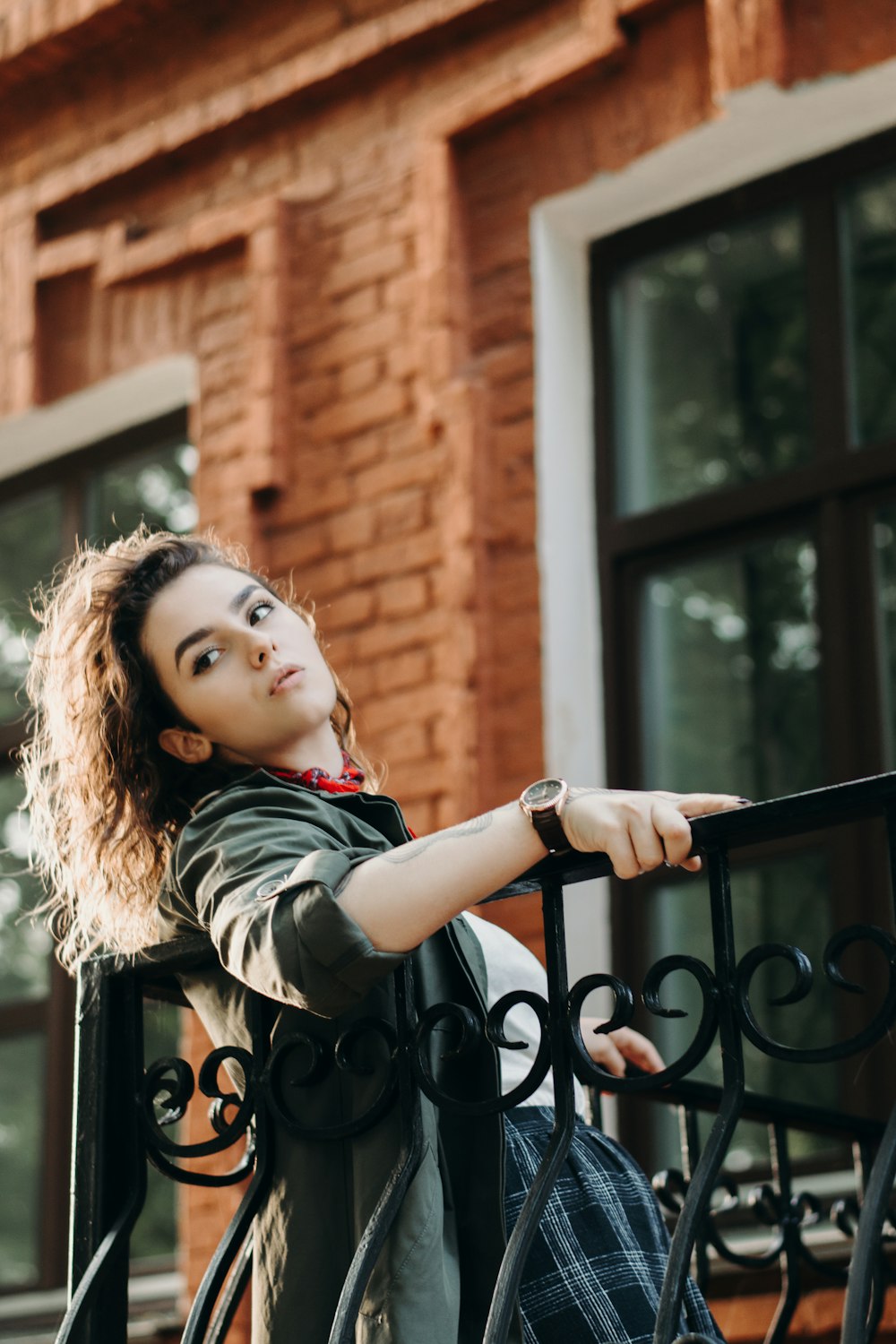 a woman leaning on a railing in front of a brick building