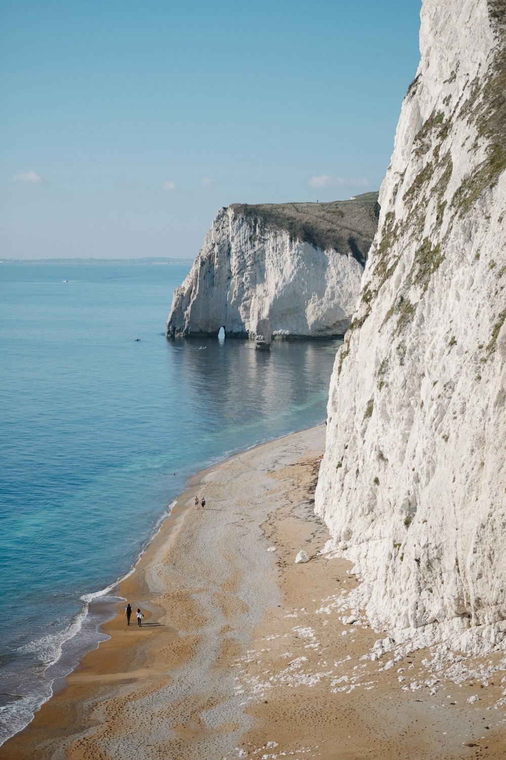 a sandy beach next to a large white cliff