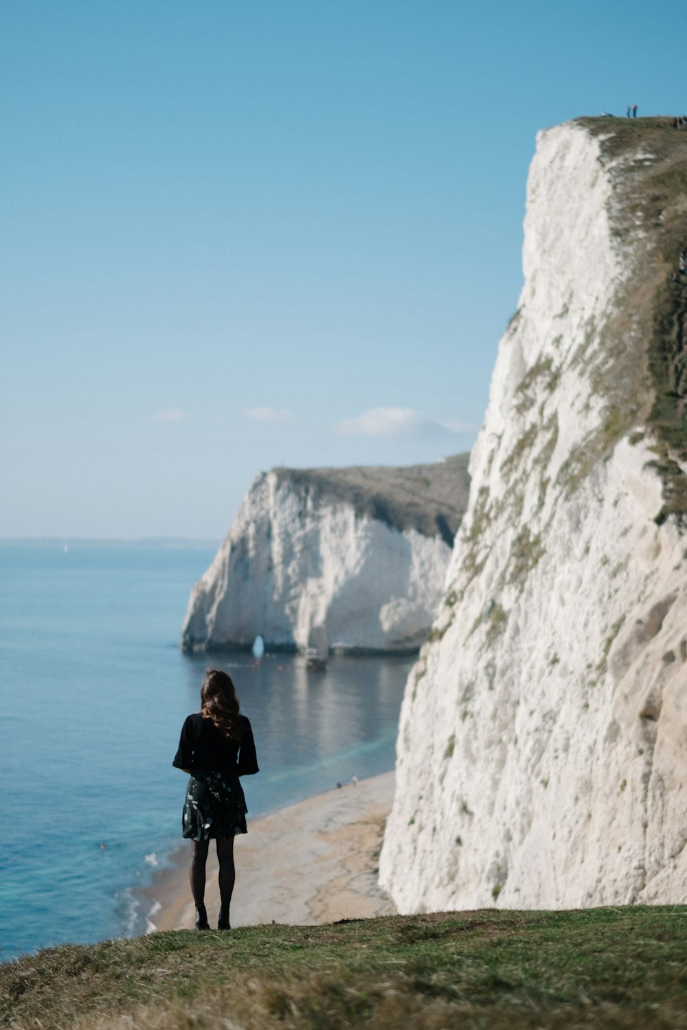 a woman standing on the edge of a cliff overlooking the ocean