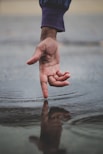 person touching body of water and creating ripples