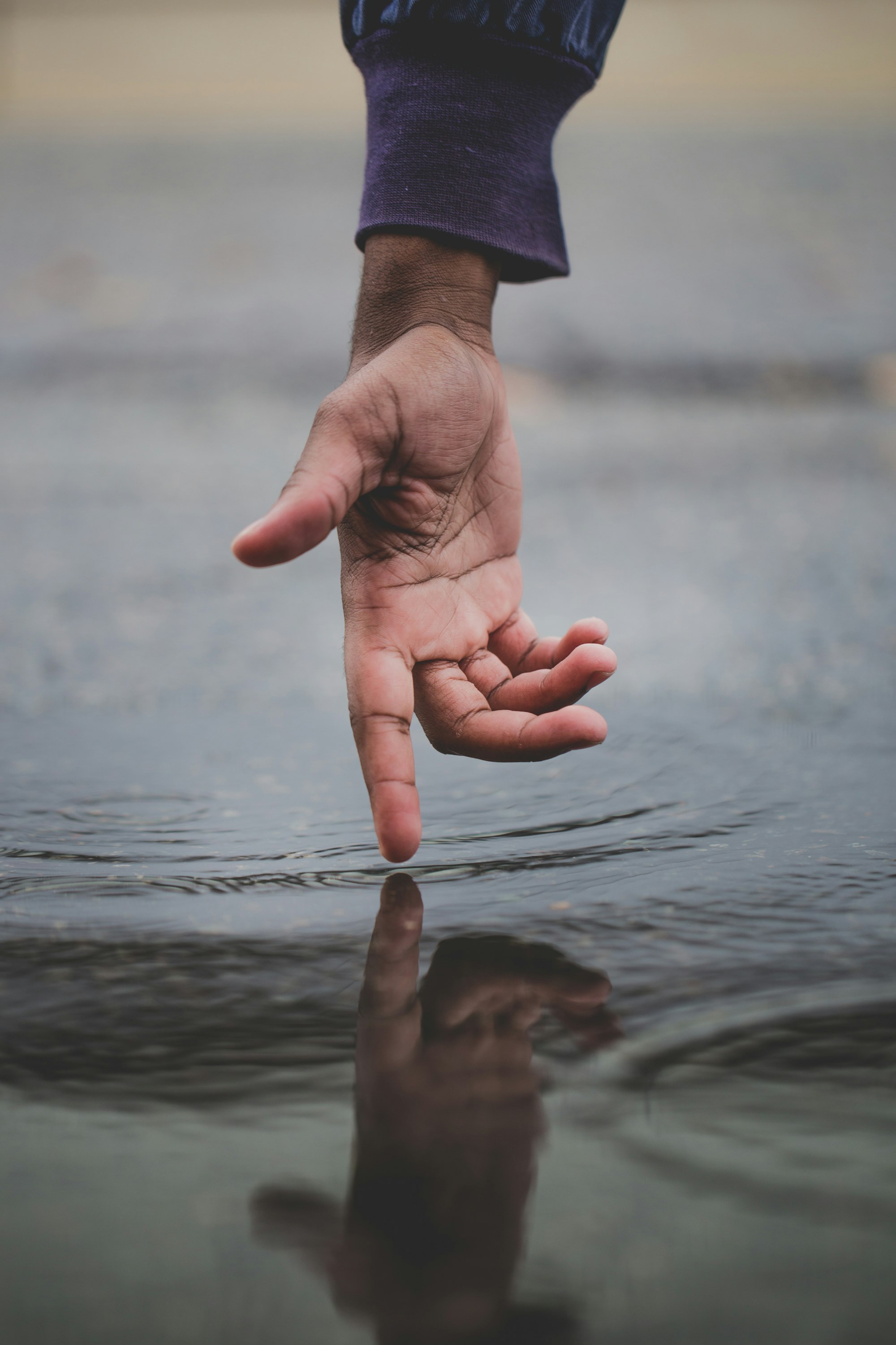 Person touching body of water and creating ripples. Photo by Nick Moore.