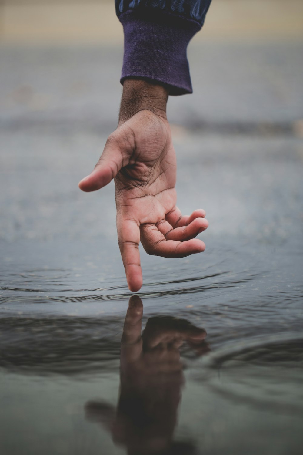 persona che tocca lo specchio d'acqua e crea increspature