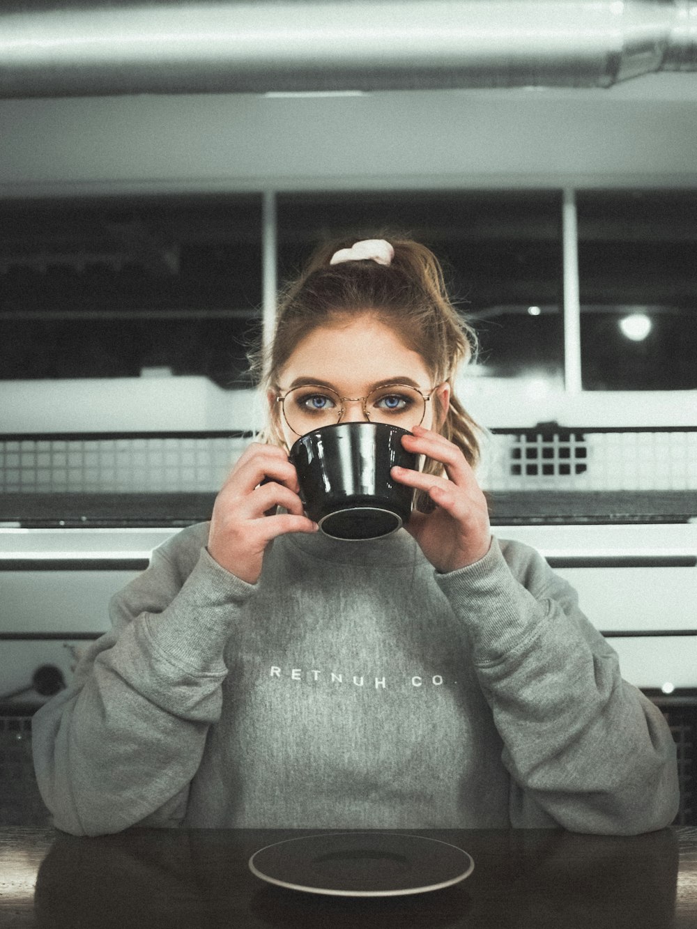 woman wearing glasses holding black ceramic mug