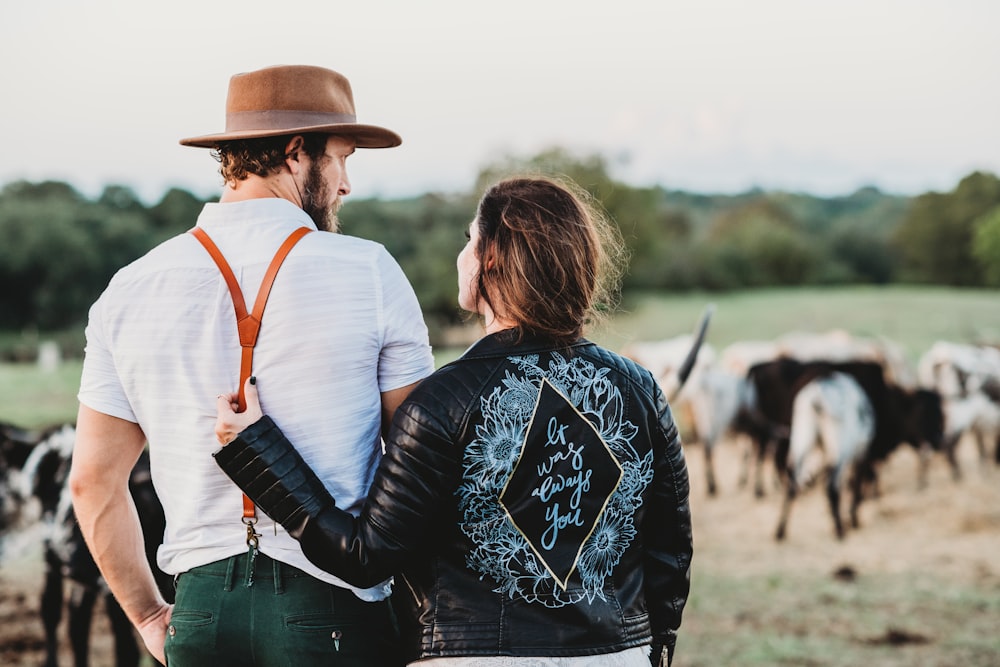 man and woman on green field with cattles