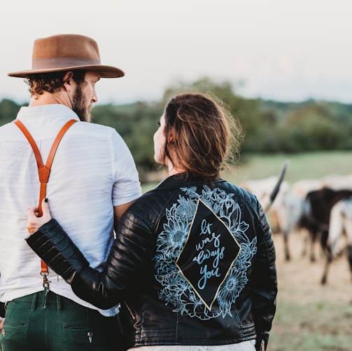 man and woman on green field with cattles