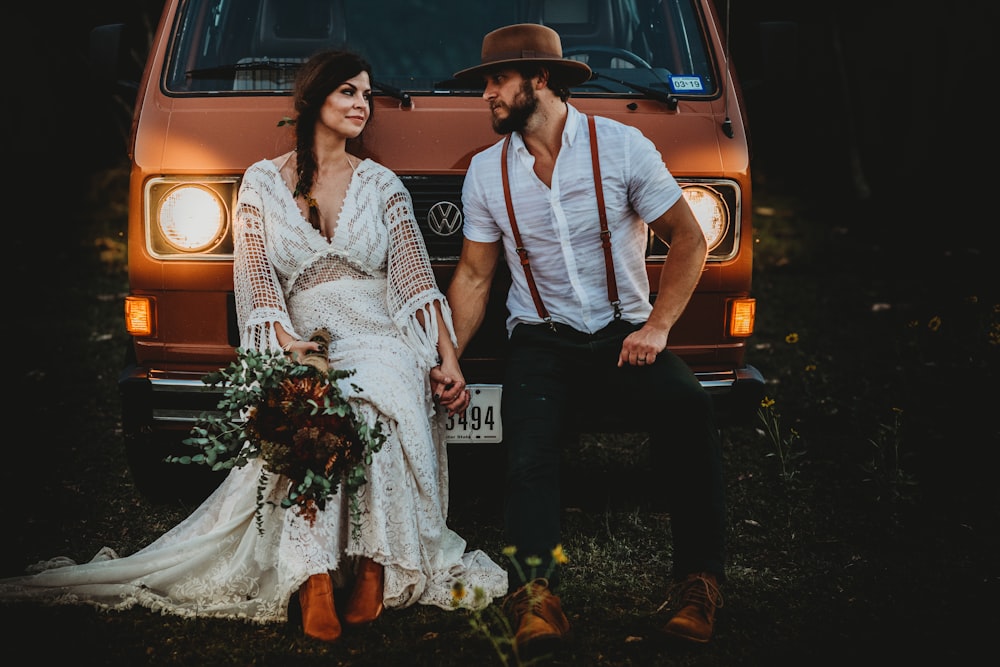 man holding hands of woman while leaning on brown Volkswagen vehicle