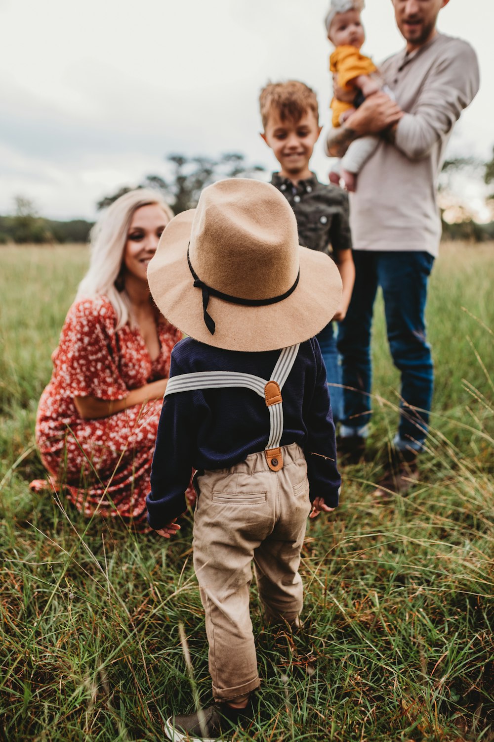 woman sitting on grass while facing boy in brown hat