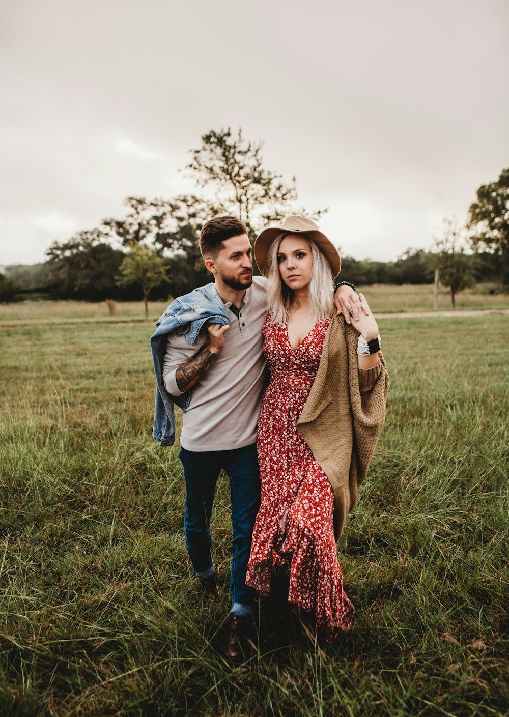 man holding woman while standing on grass area at daytime