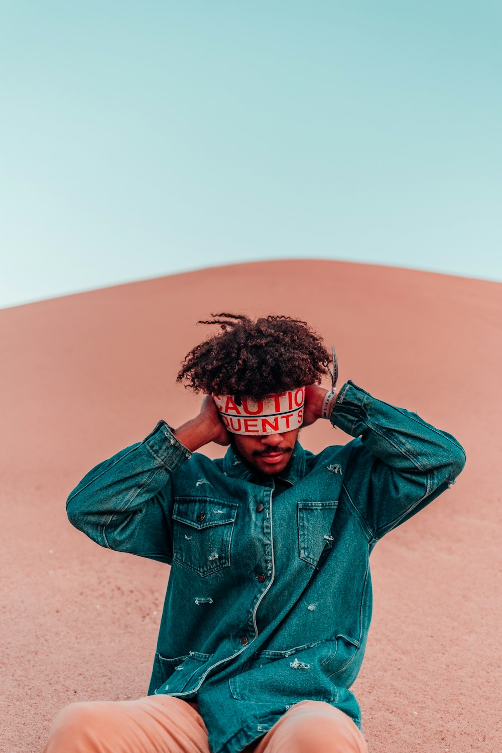 man in blue denim jacket covering ears