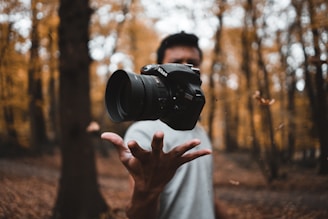 Close-up shot of a person reaching towards a suspended camera lens, emphasizing cultural document