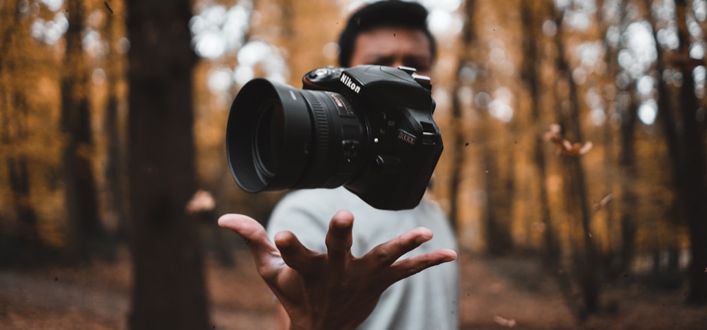 black DSLR camera floating over man's hand at the woods