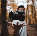 black DSLR camera floating over man's hand at the woods