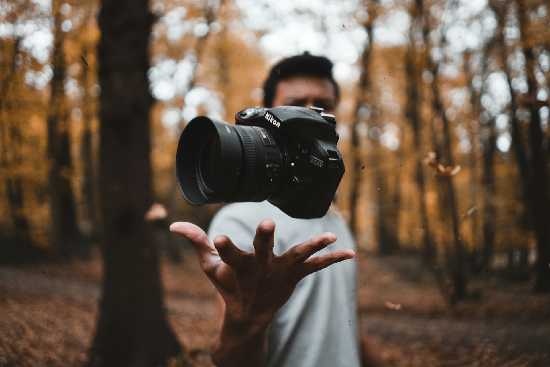 black DSLR camera floating over man's hand at the woods