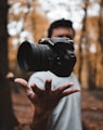 black DSLR camera floating over man's hand at the woods