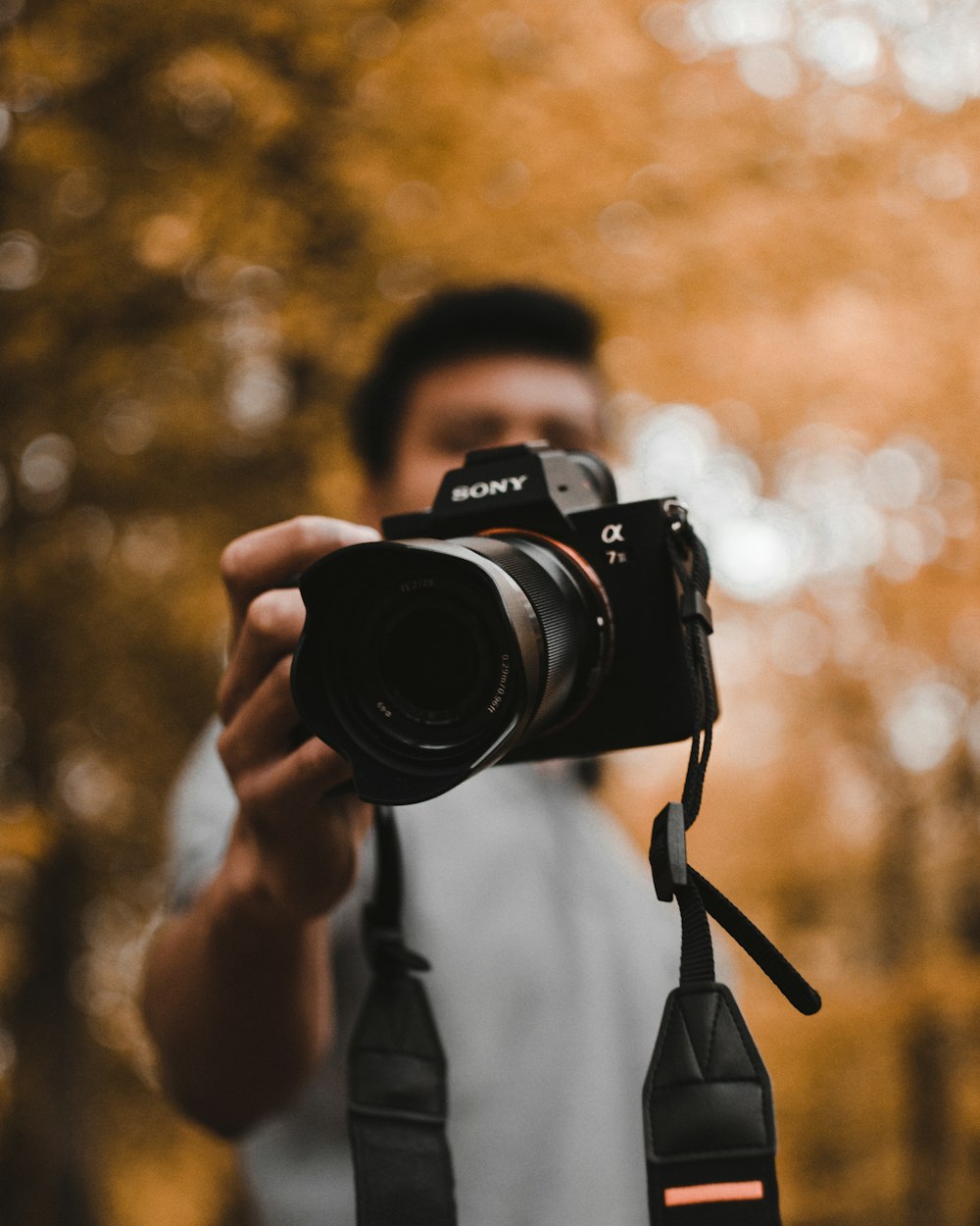 homem segurando a câmera Sony DSLR durante o dia