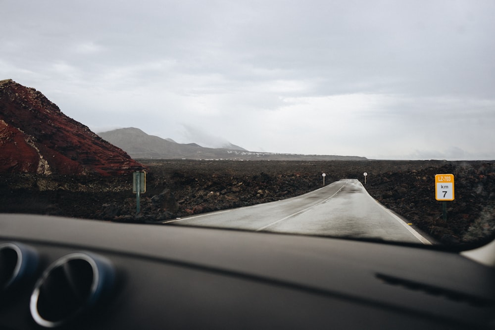 a car driving down a road next to a mountain