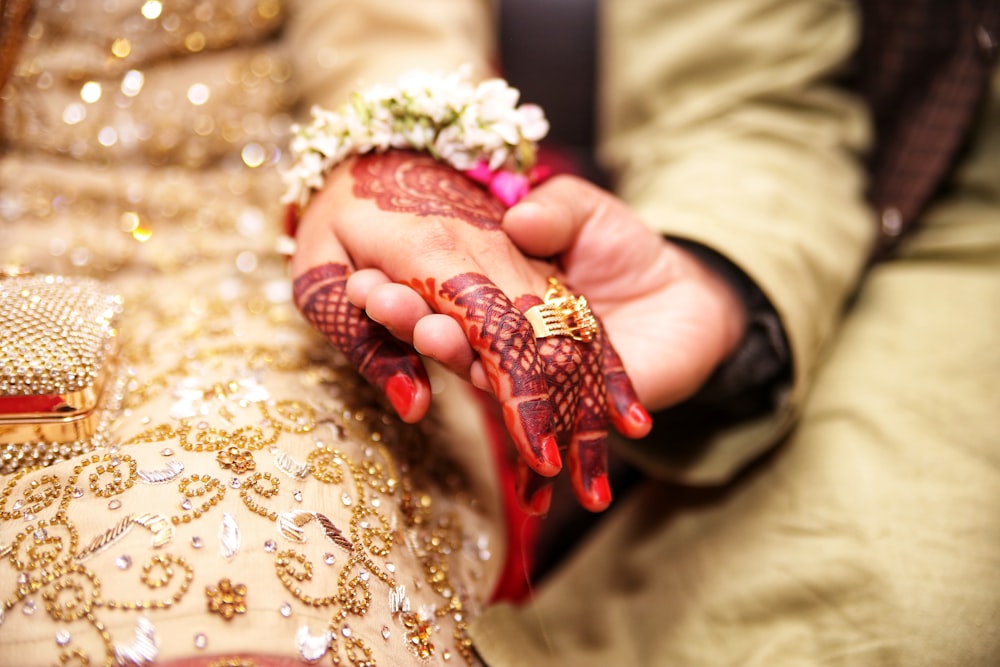 Person, die Händchen hält und einen goldfarbenen Ring trägt