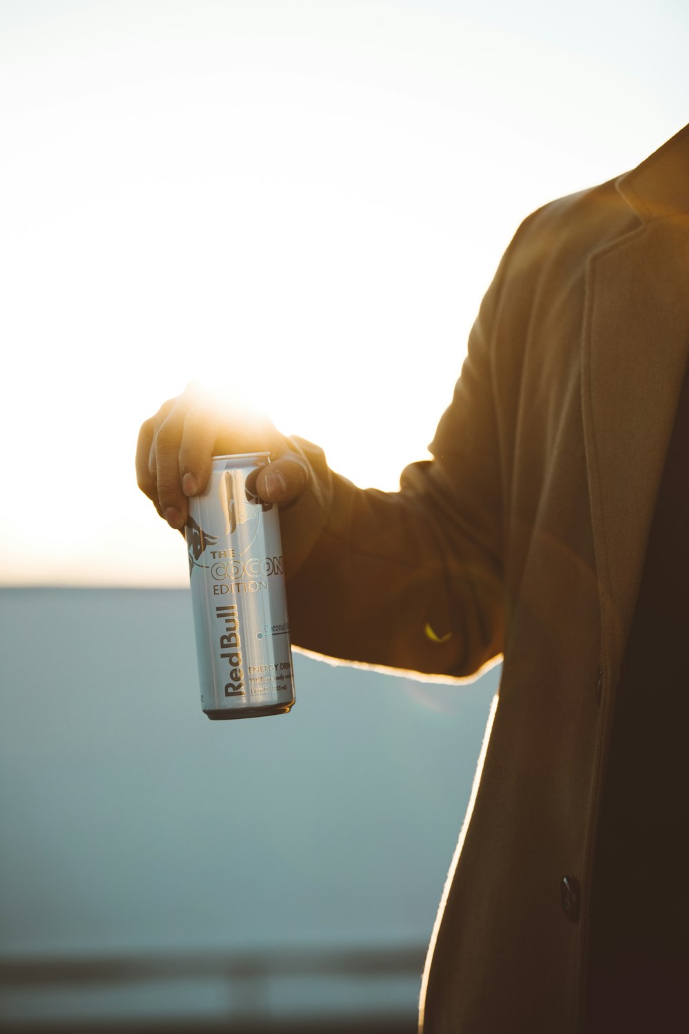 Person, die tagsüber eine mit RedBull beschriftete Dose in der Hand hält