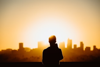 A peaceful rooftop sunset with a silhouette practicing tai chi, city skyline glowing softly behind.