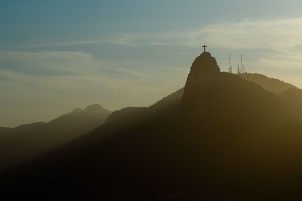 silhouette of cross on top of mountain at daytime