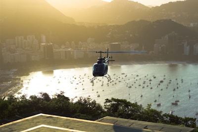 Luxury helicopter hovering over a city skyline at sunset.