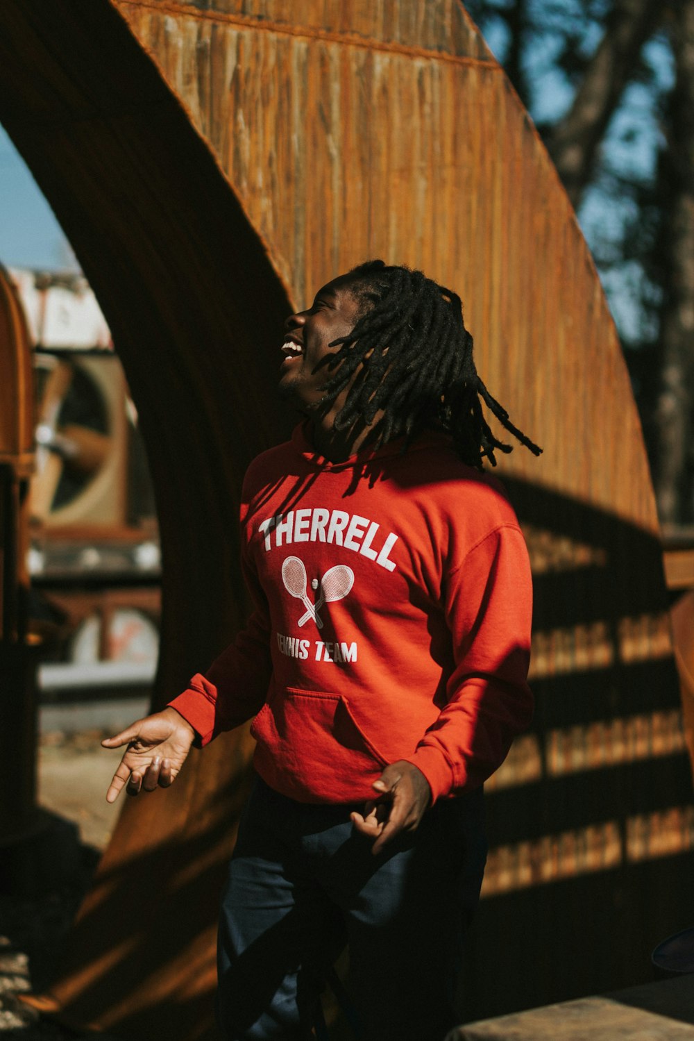 standing man wearing orange sweater during daytime