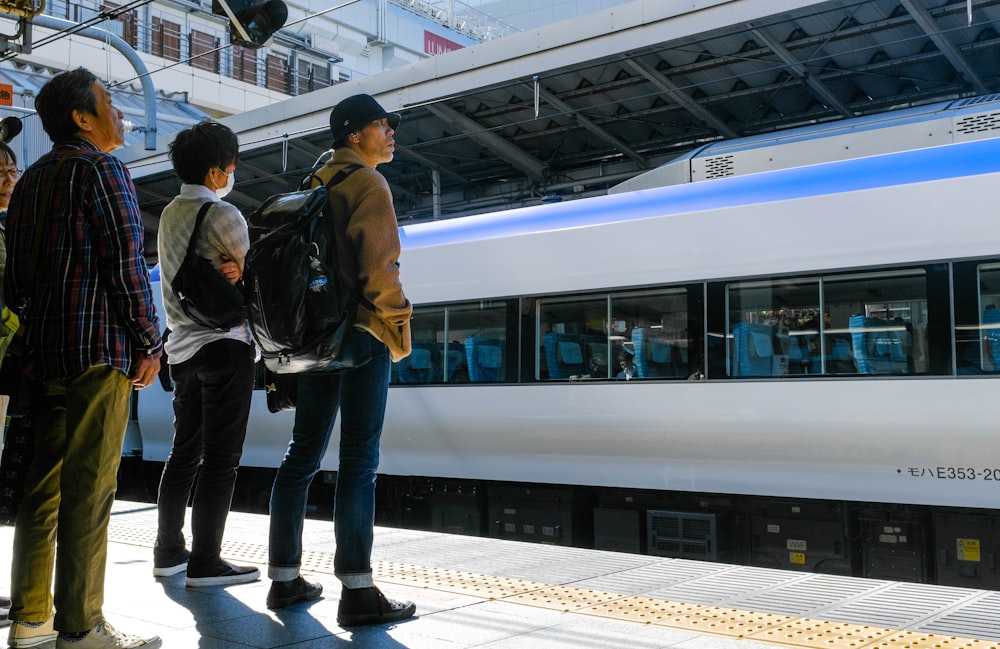 trois hommes debout devant un train à grande vitesse