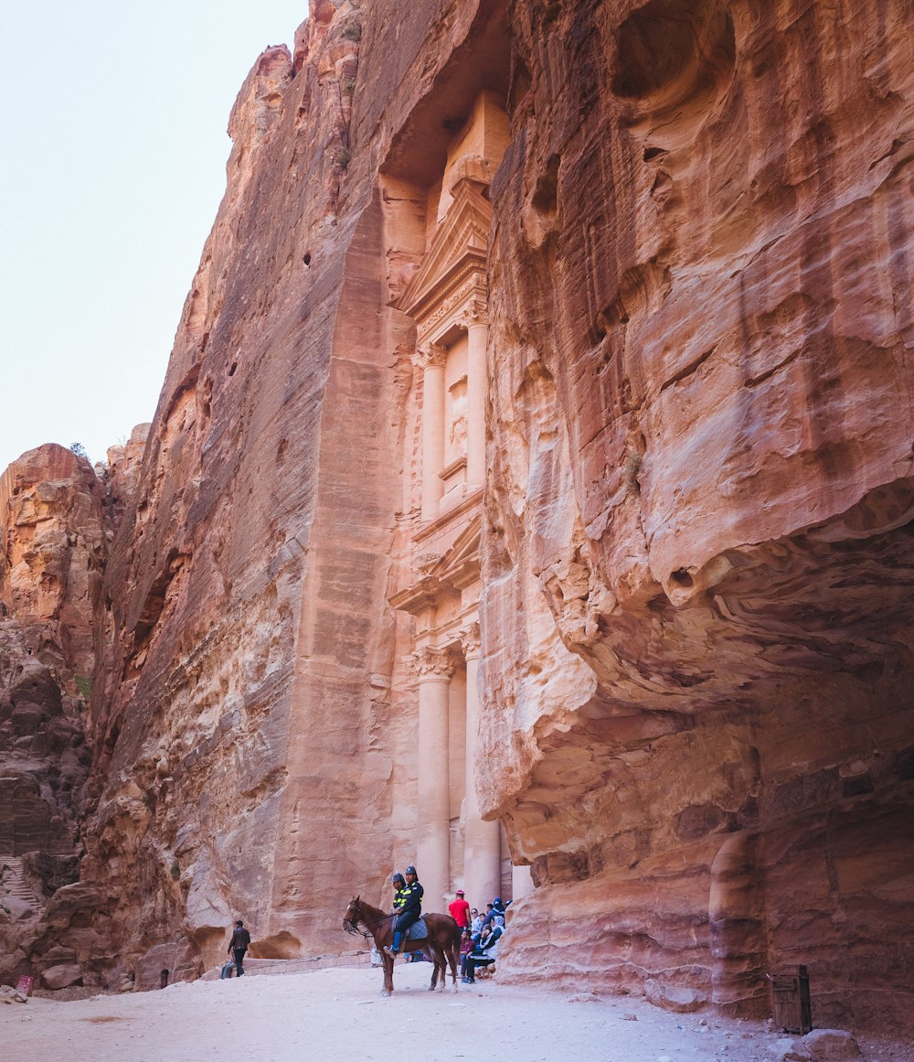 group of people riding horse beside rock formation