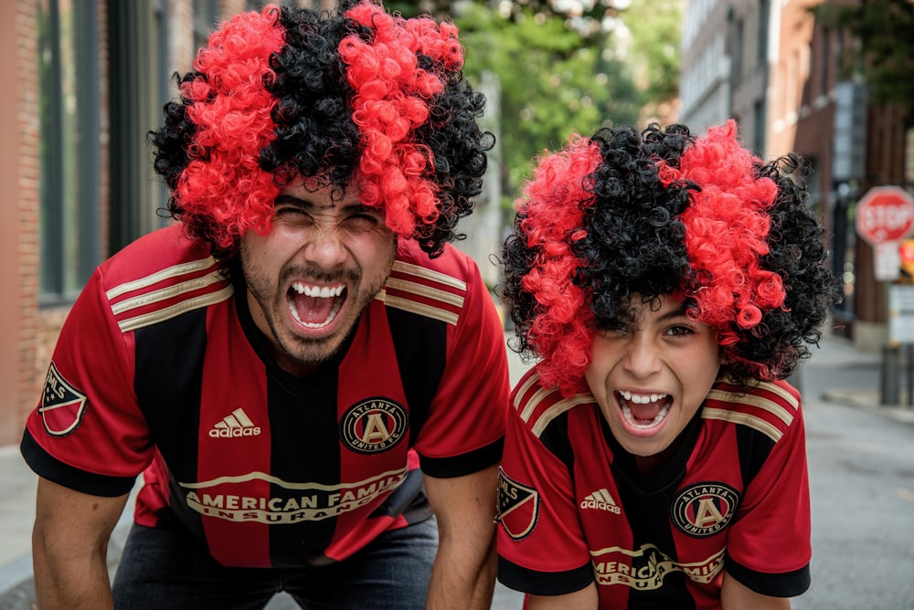 homme et garçon portant une perruque bouclée noire et rouge et souriant