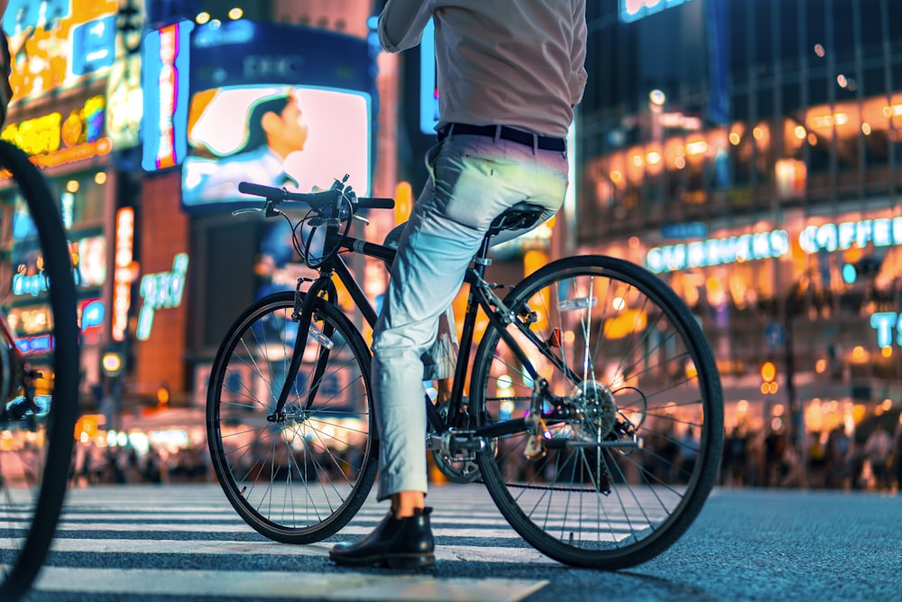 homem andando de bicicleta perto de edifícios durante a noite