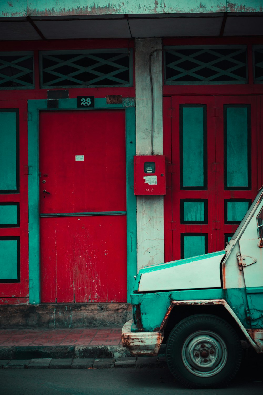 white and green vehicle near red wooden door during daytime