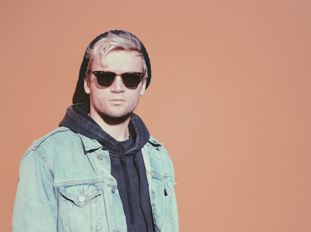 standing man in blue denim jacket beside orange surface